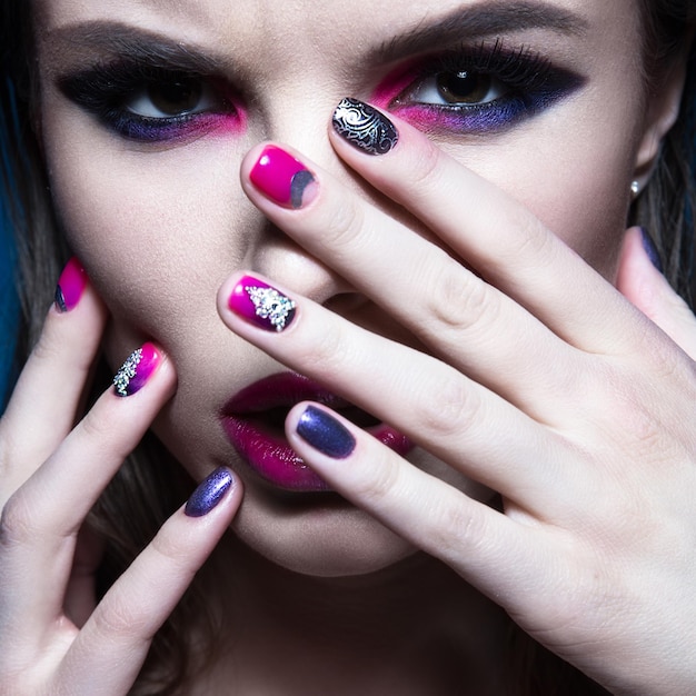 Hermosa chica con maquillaje de moda creativo brillante y esmalte de uñas colorido diseño de belleza de arte