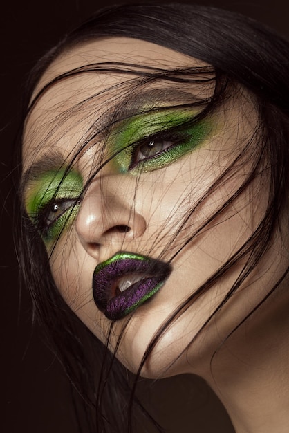 Hermosa chica con maquillaje verde primavera y cara de belleza de labios de vampiro