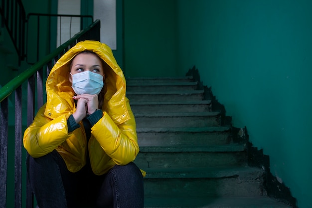 Hermosa chica en máscara médica en un edificio abandonado aislado en cuarentena