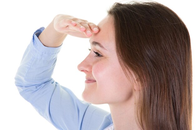 Hermosa chica mirando lejos sosteniendo su mano en la frente escucha sus ojos