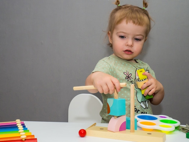 Hermosa chica monta un constructor en la mesa de los niños.