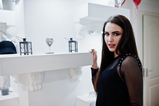 Hermosa chica morena en la boutique de la tienda de ropa en vestido negro