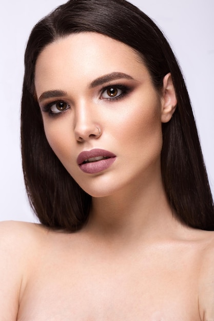 Hermosa chica morena con un cabello perfectamente liso y maquillaje clásico Rostro de belleza