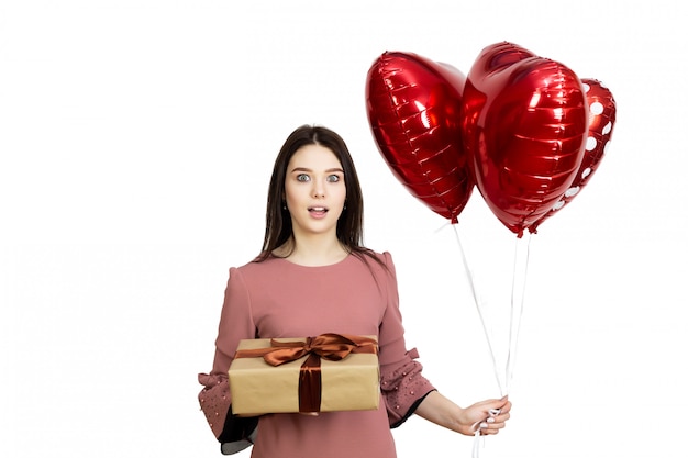 Hermosa chica morena con globos rojos y un regalo