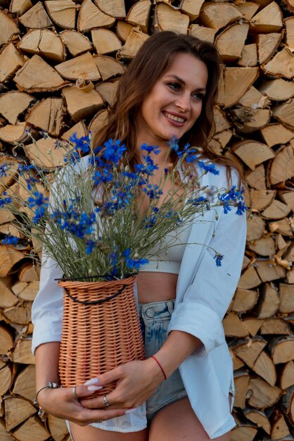 Hermosa chica morena hermosa increíble posando con flores en el fondo de la leña