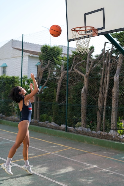 una hermosa chica morena juega al baloncesto en la cancha de baloncesto