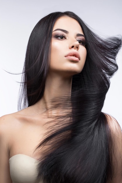 Hermosa chica morena en movimiento con un cabello perfectamente liso y maquillaje clásico Rostro de belleza