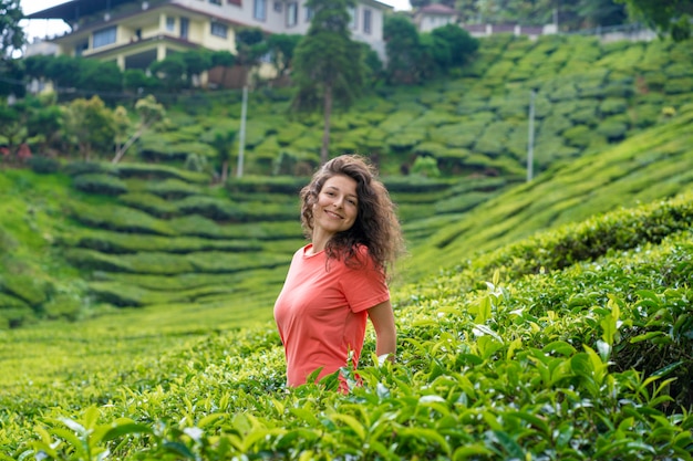 Hermosa chica morena posando en medio del valle del té entre arbustos de té verde.