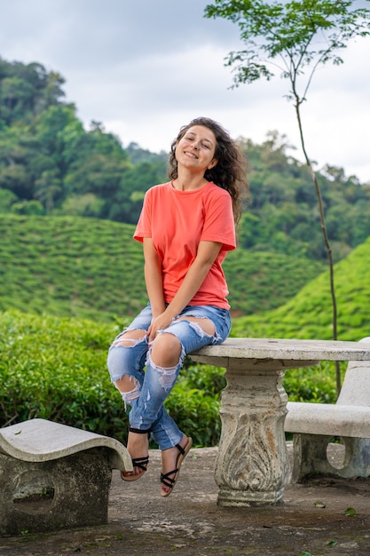 Hermosa chica morena posando en medio del valle del té entre arbustos de té verde.