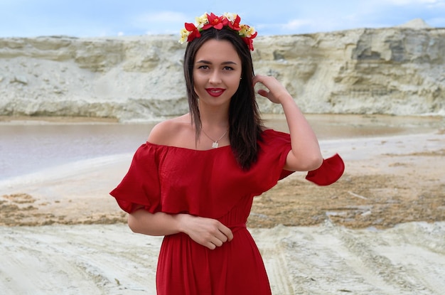 Hermosa chica morena con un vestido rojo brillante en el desierto