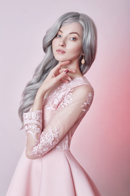 Hermosa chica de muñeca de anime en vestido rosa sobre fondo rosa. Una chica con el pelo largo y rubio ceniza. Mirada fabulosa de mujer heroína anime