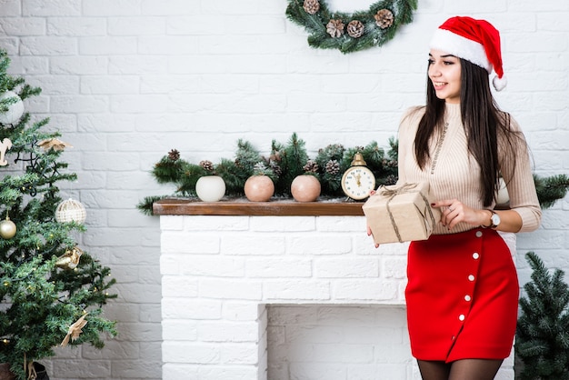 Hermosa chica en Navidad habitación decorada con caja de regalo