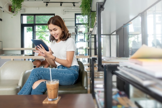 Hermosa chica de negocios trabajando con tableta, teléfono inteligente y tomando café en la cafetería