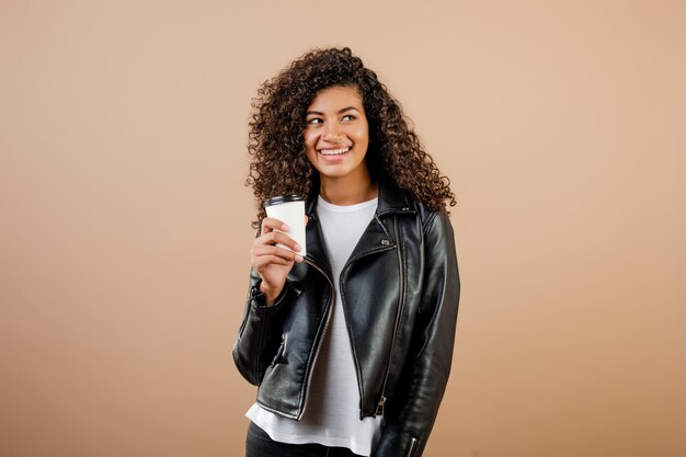 Hermosa chica negra con café para llevar taza aislada sobre marrón