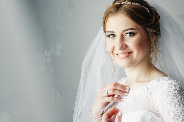 Hermosa chica, novia con un vestido blanco en el fondo del apartamento. Boda, reunión de novias, creación familiar.