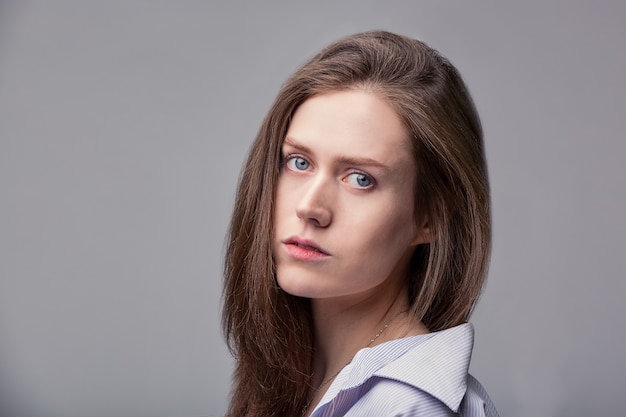 Hermosa chica con ojos azules posando sobre espacio gris