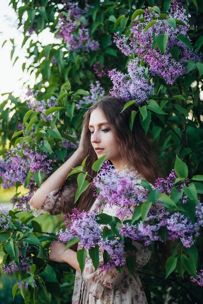 Hermosa chica de ojos grandes cerca del árbol lila.