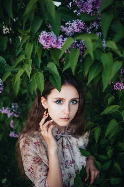 Hermosa chica de ojos grandes cerca del árbol lila.