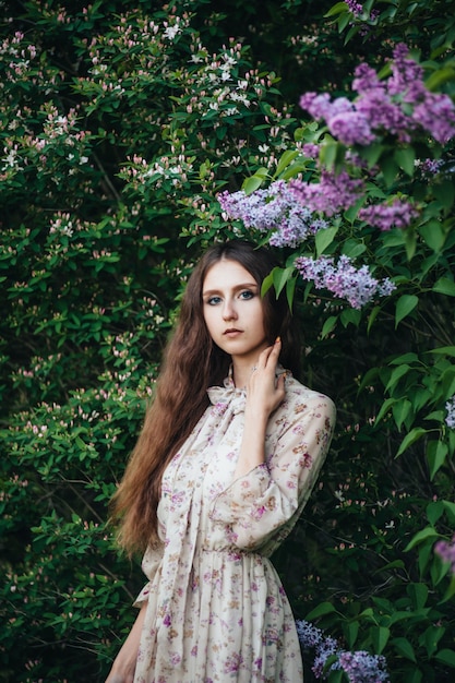 Hermosa chica de ojos grandes cerca del árbol lila.