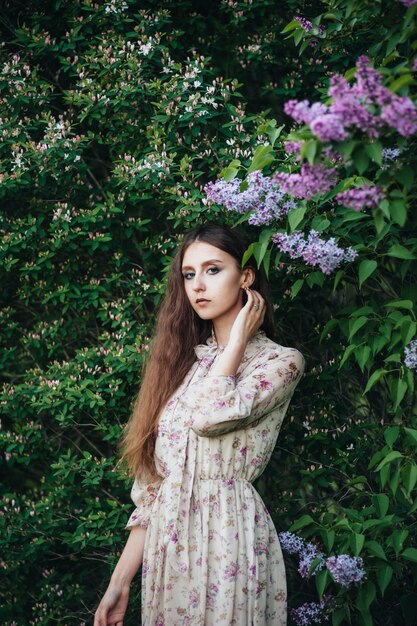 Hermosa chica de ojos grandes cerca del árbol lila.