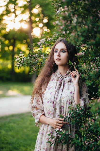 Hermosa chica de ojos grandes cerca del árbol lila.