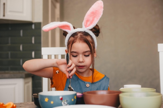 Hermosa chica en orejas de conejo pinta huevos de Pascua