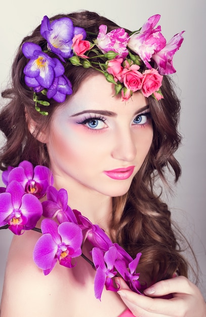 Hermosa chica con orquídeas y fresias en el cabello