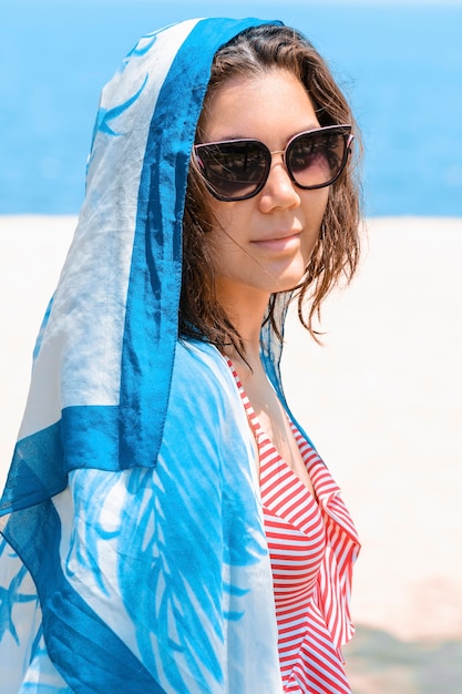 Hermosa chica con pañuelo en la cabeza y gafas de sol para protegerse del sol