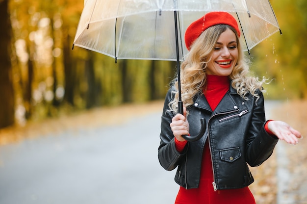 Hermosa chica con paraguas en el parque de otoño.