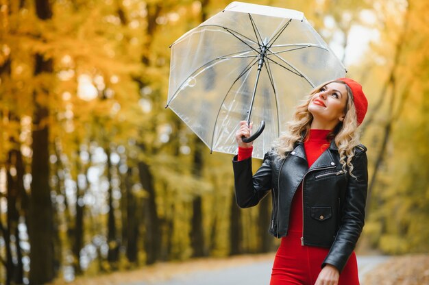 Hermosa chica con paraguas en el parque de otoño.