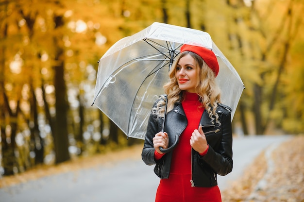 Hermosa chica con paraguas en el parque de otoño.