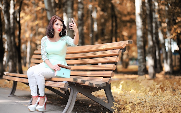 Hermosa chica en un parque caducifolio de otoño por la tarde