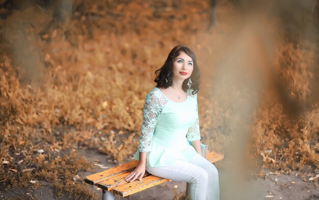 Hermosa chica en un parque caducifolio de otoño por la tarde