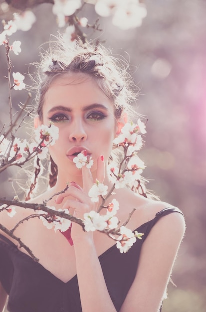 Hermosa chica en el parque de primavera con flores retrato de estilo de vida mujer feliz con cerezo floreciente Cuidado de la piel y belleza femenina en el jardín disfrutando de la naturaleza Concepto de primavera Serie