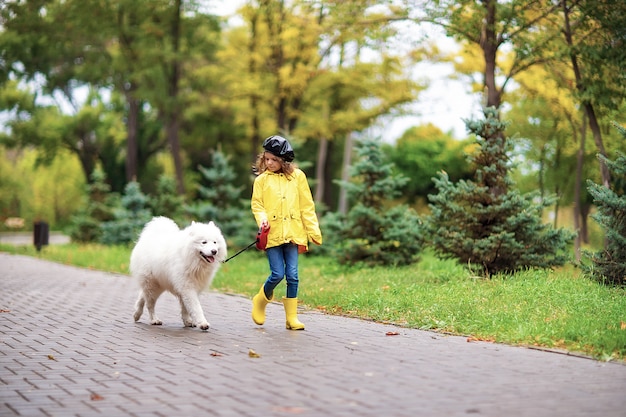 Hermosa chica en un paseo con un hermoso perro en un parque al aire libre