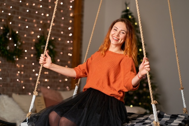 Una hermosa chica pelirroja se balancea en su habitación en la noche de Navidad