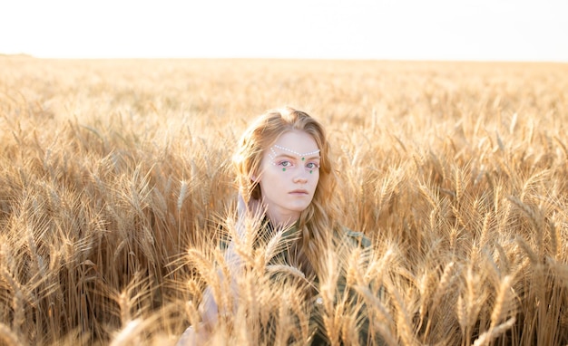 Hermosa chica pelirroja en un campo de centeno al atardecer