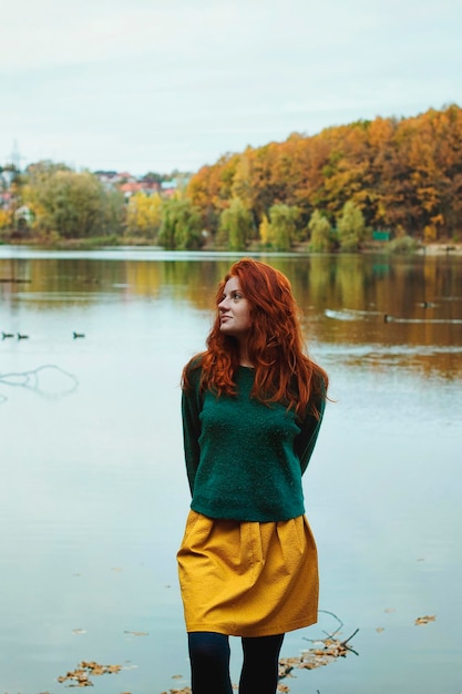 hermosa chica pelirroja con pecas, ojos azules en el parque de otoño. Estilo de otoño. suéter, suéter cálido