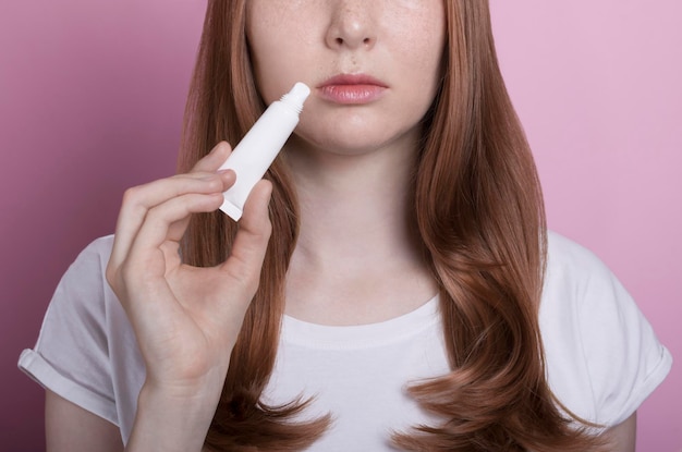 Hermosa chica pelirroja con pecas retrato de primer plano usar lápiz labial bálsamo labial maqueta