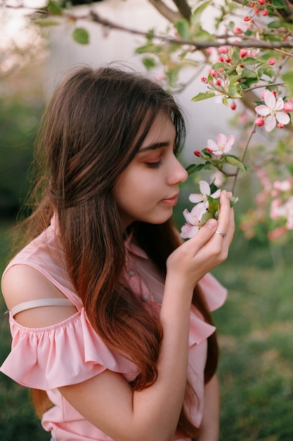 Hermosa chica pelirroja en la primavera en las ramas del manzano