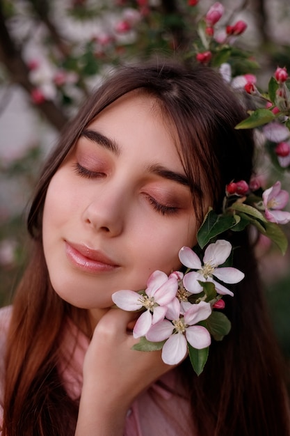 Hermosa chica pelirroja en la primavera en las ramas del manzano