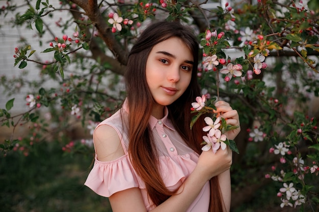 Hermosa chica pelirroja en la primavera en las ramas del manzano
