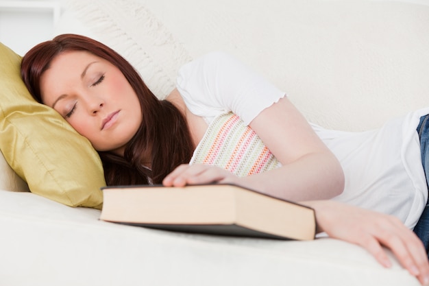 Hermosa chica pelirroja tomando un descanso mientras estudiaba en un sofá