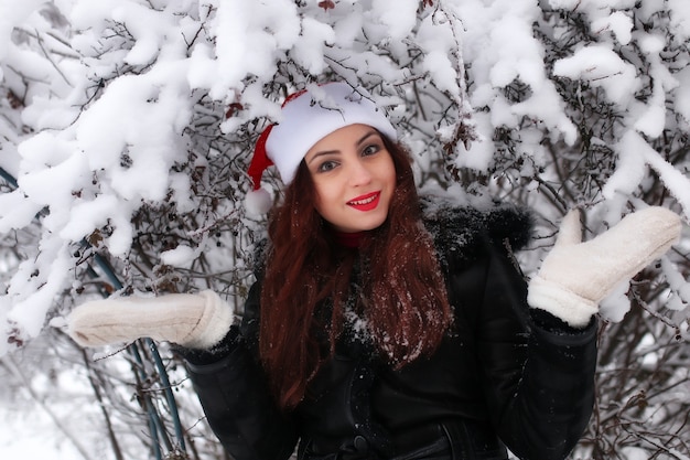 Hermosa chica pelirroja de vacaciones en una casa de campo en el norte, jugando con la nieve