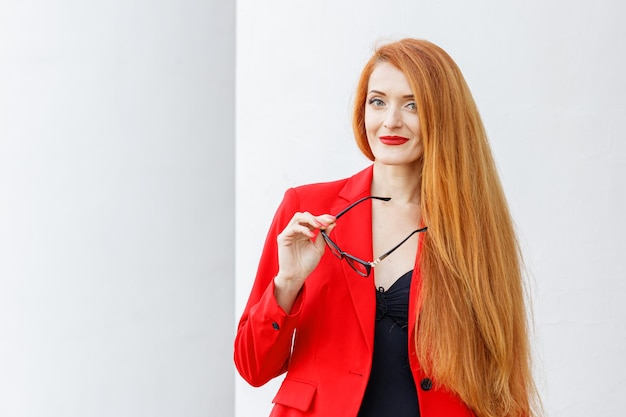 Hermosa chica pelirroja vestida con un traje de negocios rojo Retrato de negocios