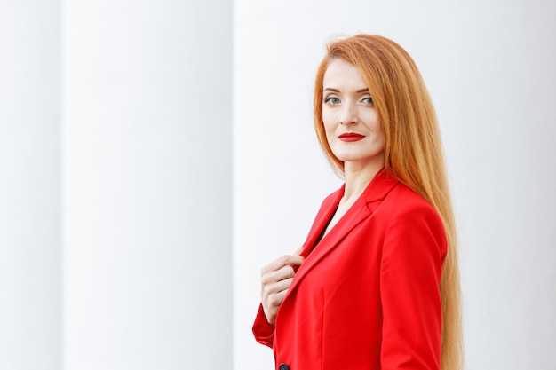 Hermosa chica pelirroja vestida con un traje de negocios rojo Retrato de negocios