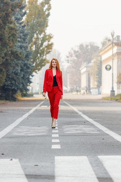 Hermosa chica pelirroja vestida con un traje de negocios rojo Retrato de negocios