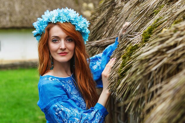 Hermosa chica pelirroja con un vestido azul ucraniano con una corona en la cabeza