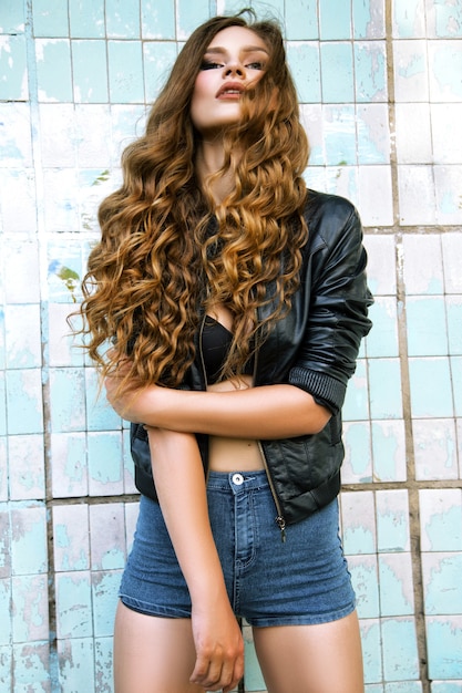 Foto hermosa chica con el pelo largo posando junto a la pared