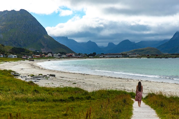 hermosa chica de pelo largo con un vestido camina por la famosa playa de ramberg (rambergstranda), noruega